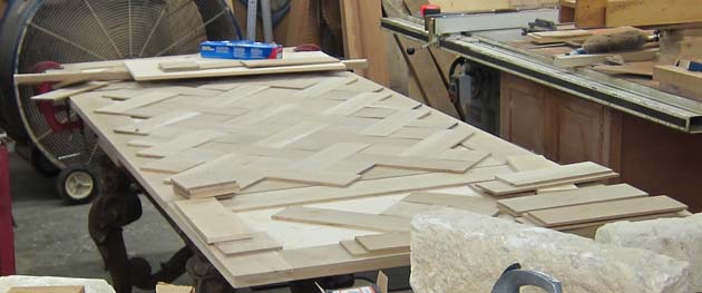 Pieces of parquet being assembled into table top for antique base